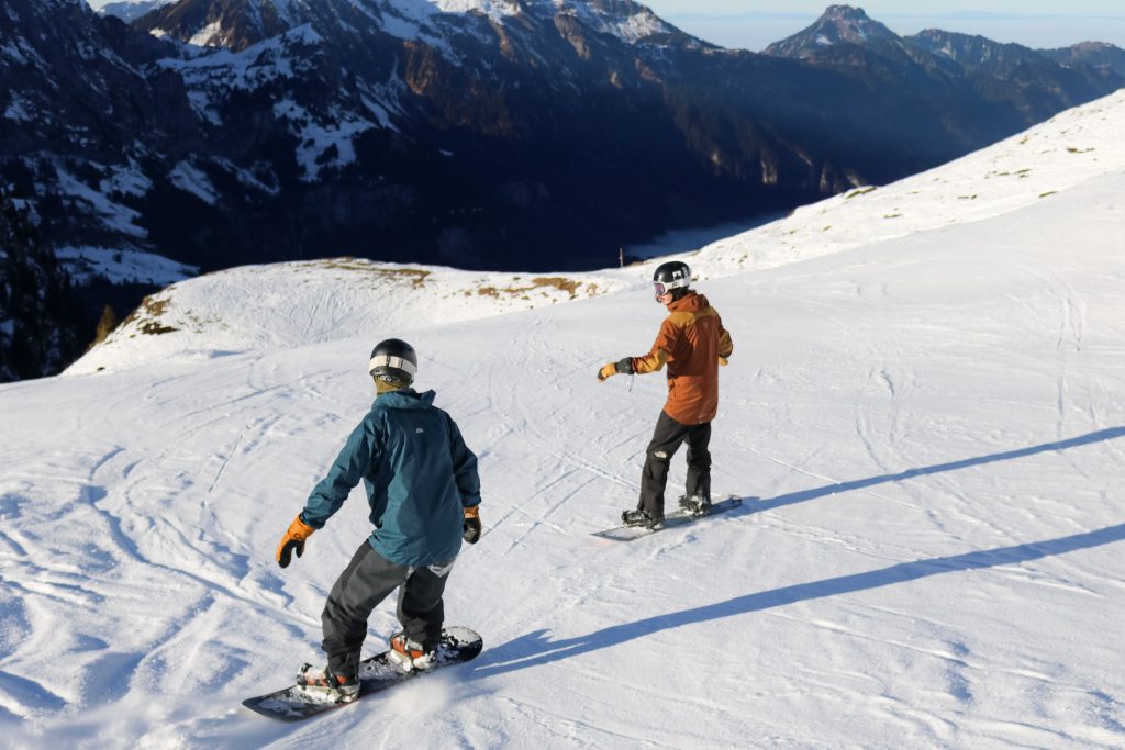 Student following a snowboard instructor during a private lesson on a wide piste in Engelberg