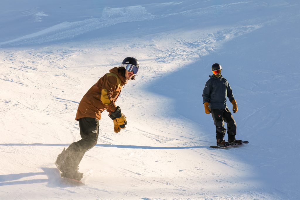 Snowboarder carving a turn with snow spray during a lesson day in Engelberg