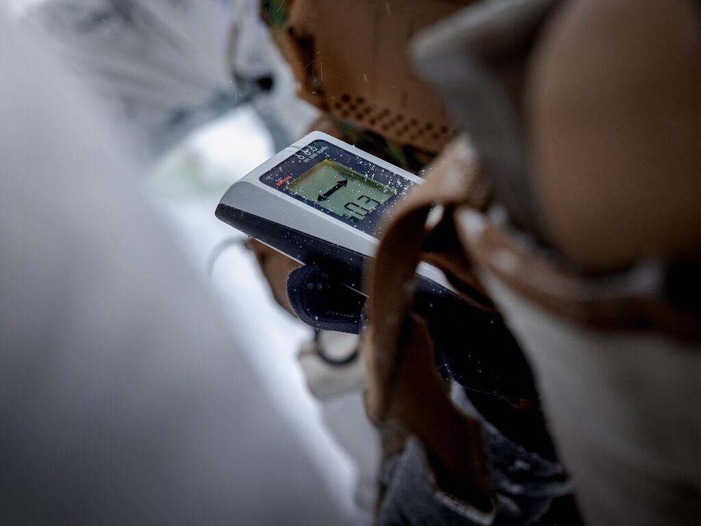 An avalanche transceiver held in a gloved hand during a check