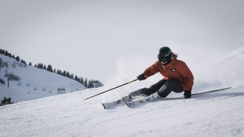 A skier carving with hips low and snow spraying off the edges
